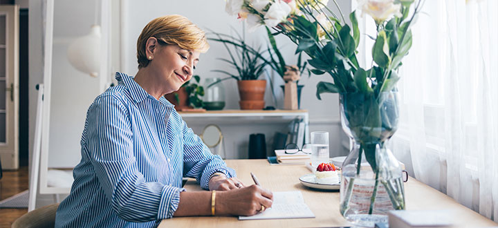 a woman sitting in a desk writing in her notebook 